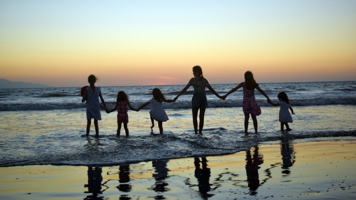 a family holding hands on the beach at sunset